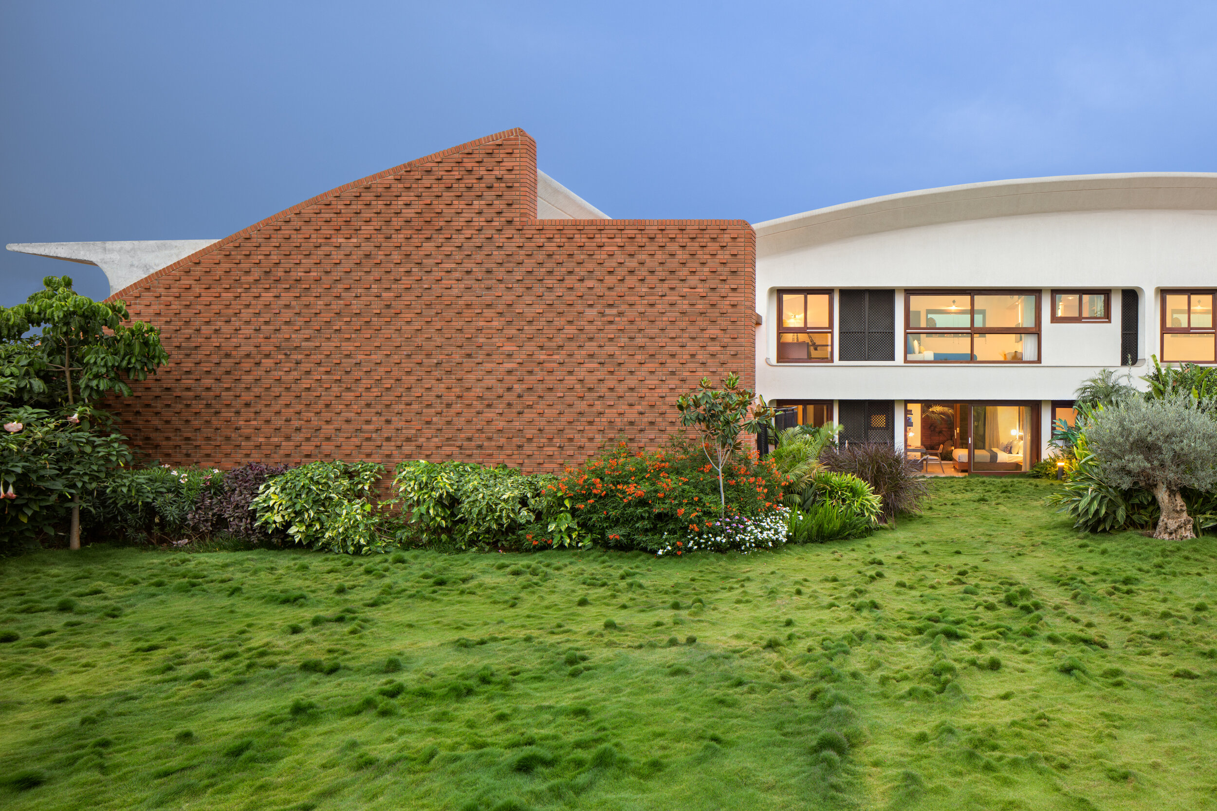 Brick and white exterior of a Total Environment home at twilight